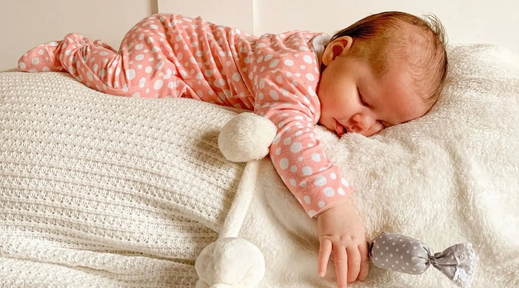 Beautiful baby gril sleeping in light pink sleepsuit