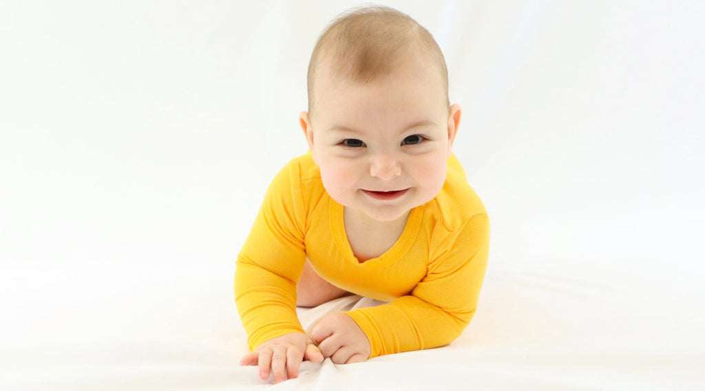 kislány baba sárga bodyban hasal - fehér háttérrel