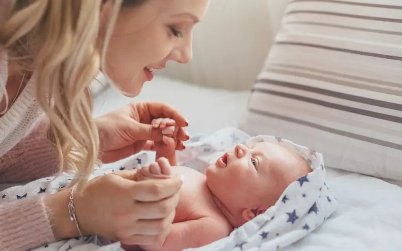 anyuka újszülött kisbabájára mosolyog